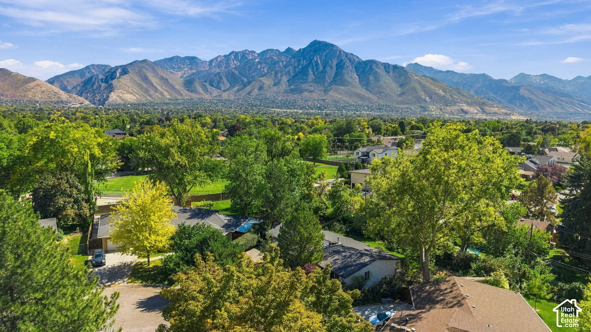 Expansive mountain backdrop with a lush, treed landscape surrounding the property that is visible at the front of the photo