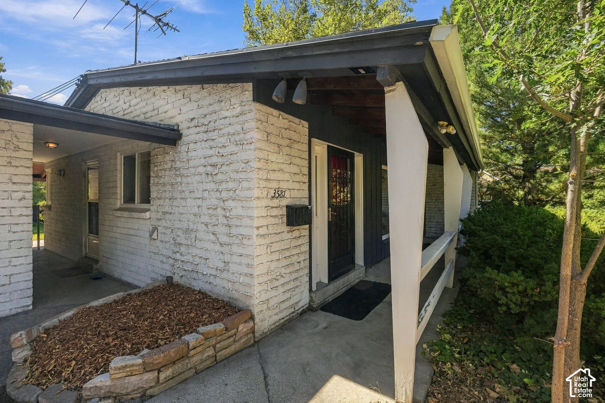 Masonry exterior with dark trim, a covered front entry, and a breezeway between the house and a garage