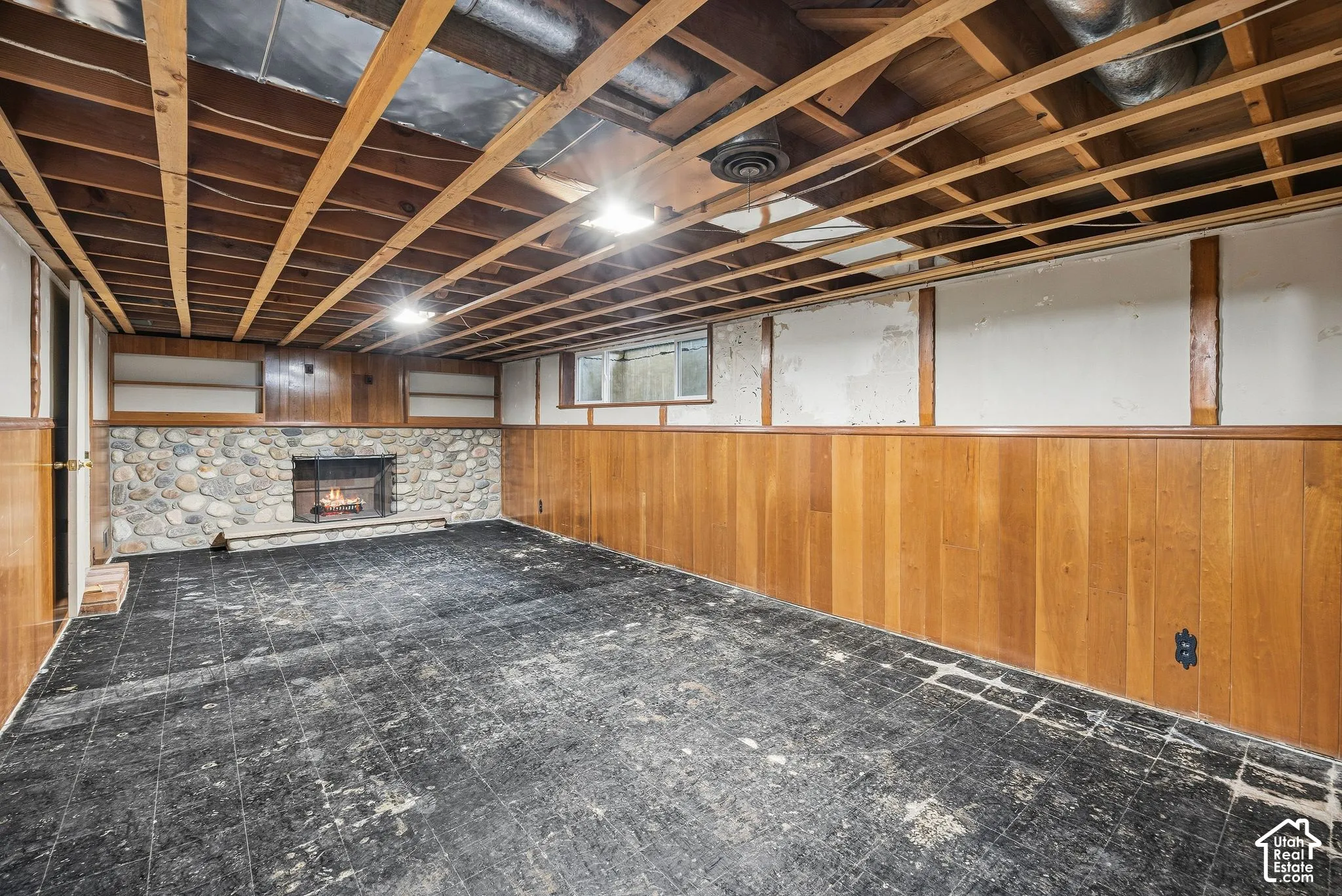 Partially finished half of the basement featuring concrete floor, stone fireplace, and built-in shelving