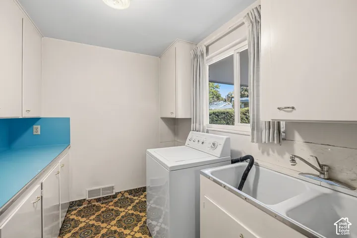 Main level laundry with cabinets, folding counter, and a window