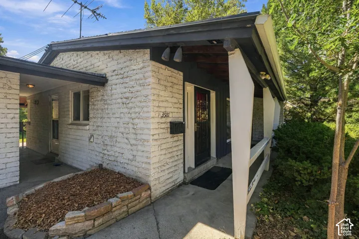 Masonry exterior with dark trim, a covered front entry, and a breezeway between the house and a garage