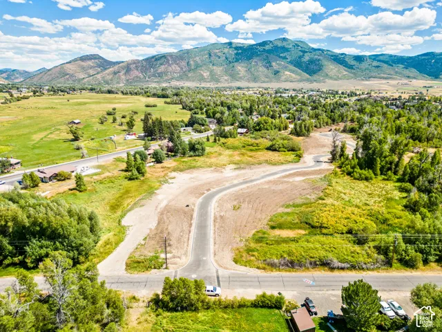 Mountain backdrop, paved cul-de-sac, cleared building sites, surrounding green landscape, nearby road access