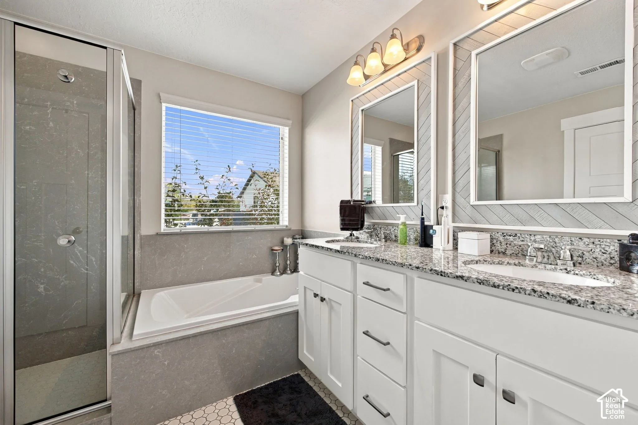 Dual vanity with granite countertops, undermount sinks, and white shaker-style cabinetry