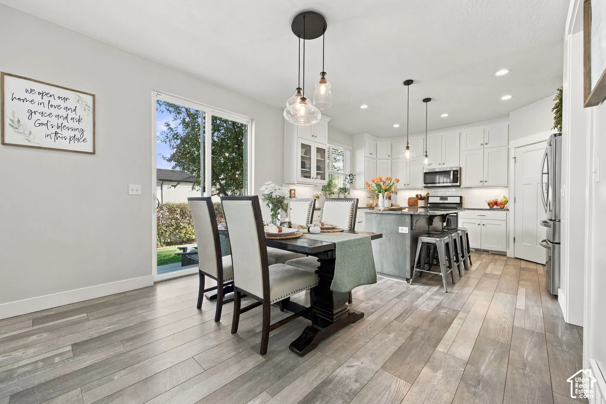 Wood-finish flooring throughout, with a white kitchen featuring stainless steel appliances and a dark-toned island