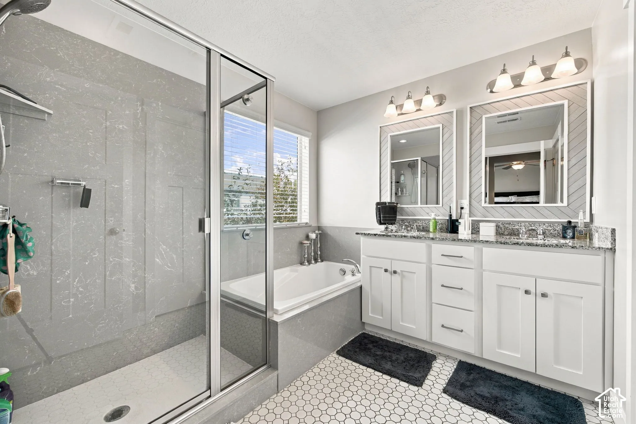 Dual vanity with granite countertops, white cabinetry, and framed mirrors