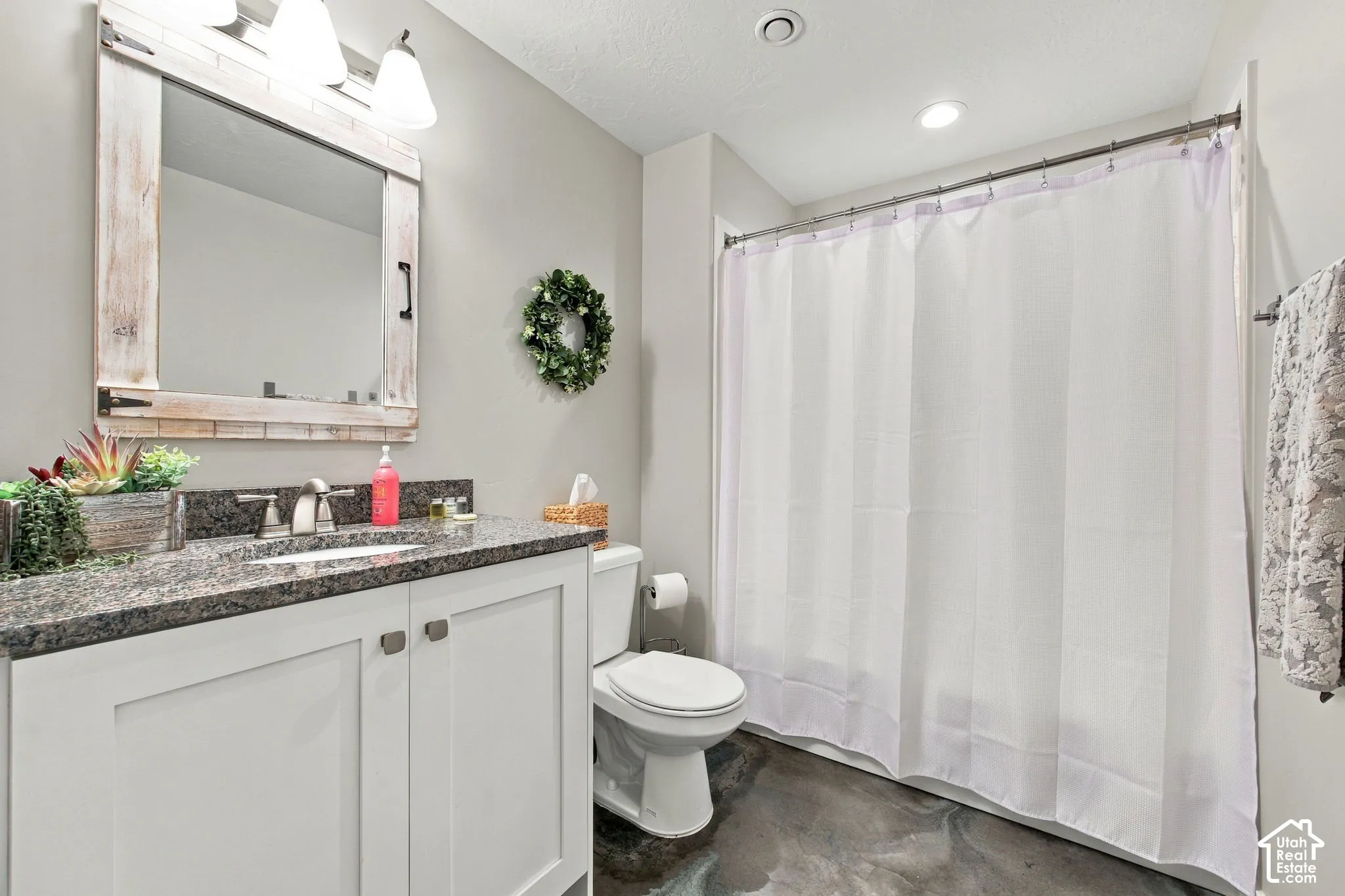 Vanity with a granite countertop, white cabinetry, and brushed nickel hardware