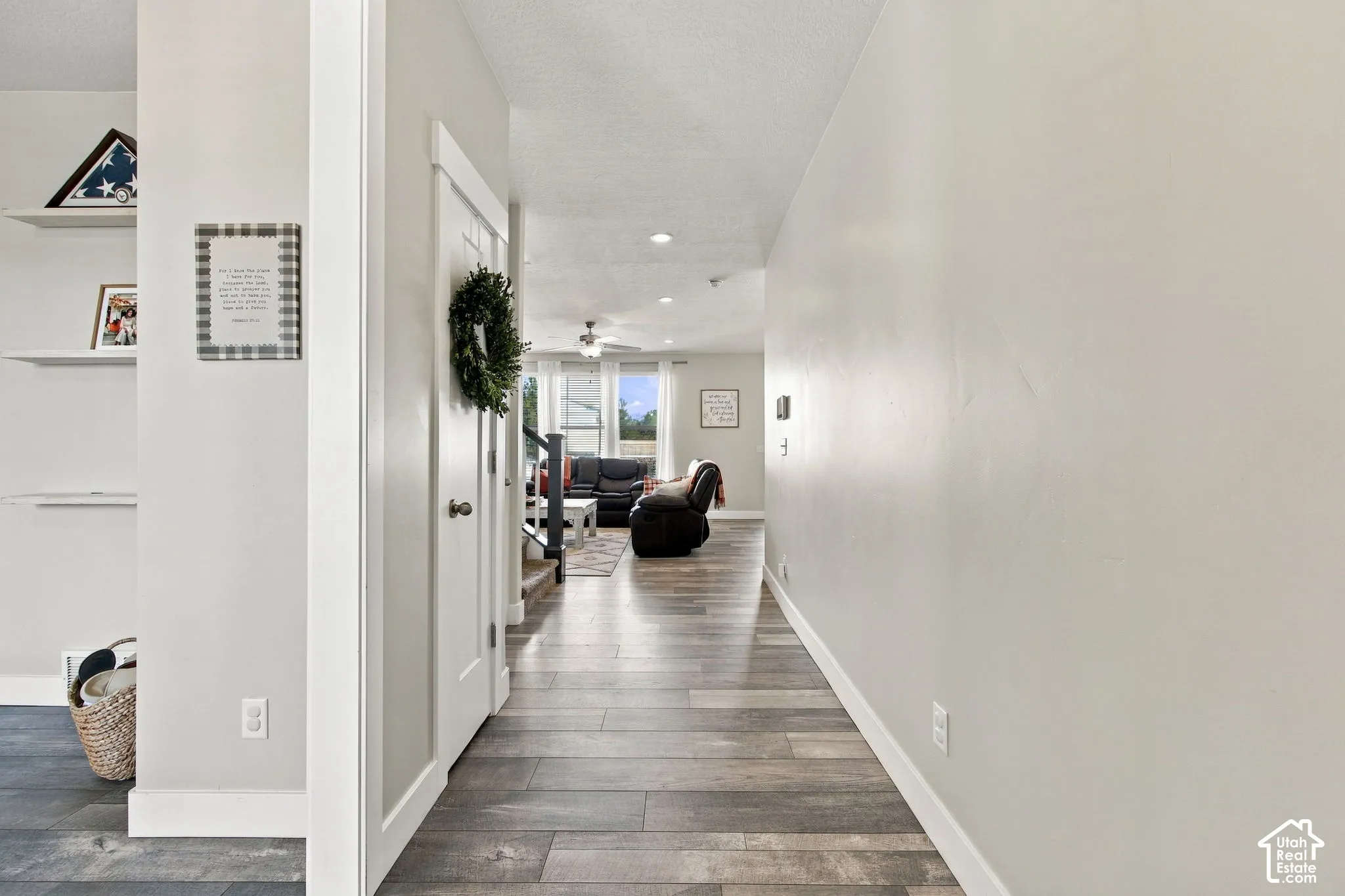 Wood-finish flooring extending throughout, leading to an open living area with recessed lighting