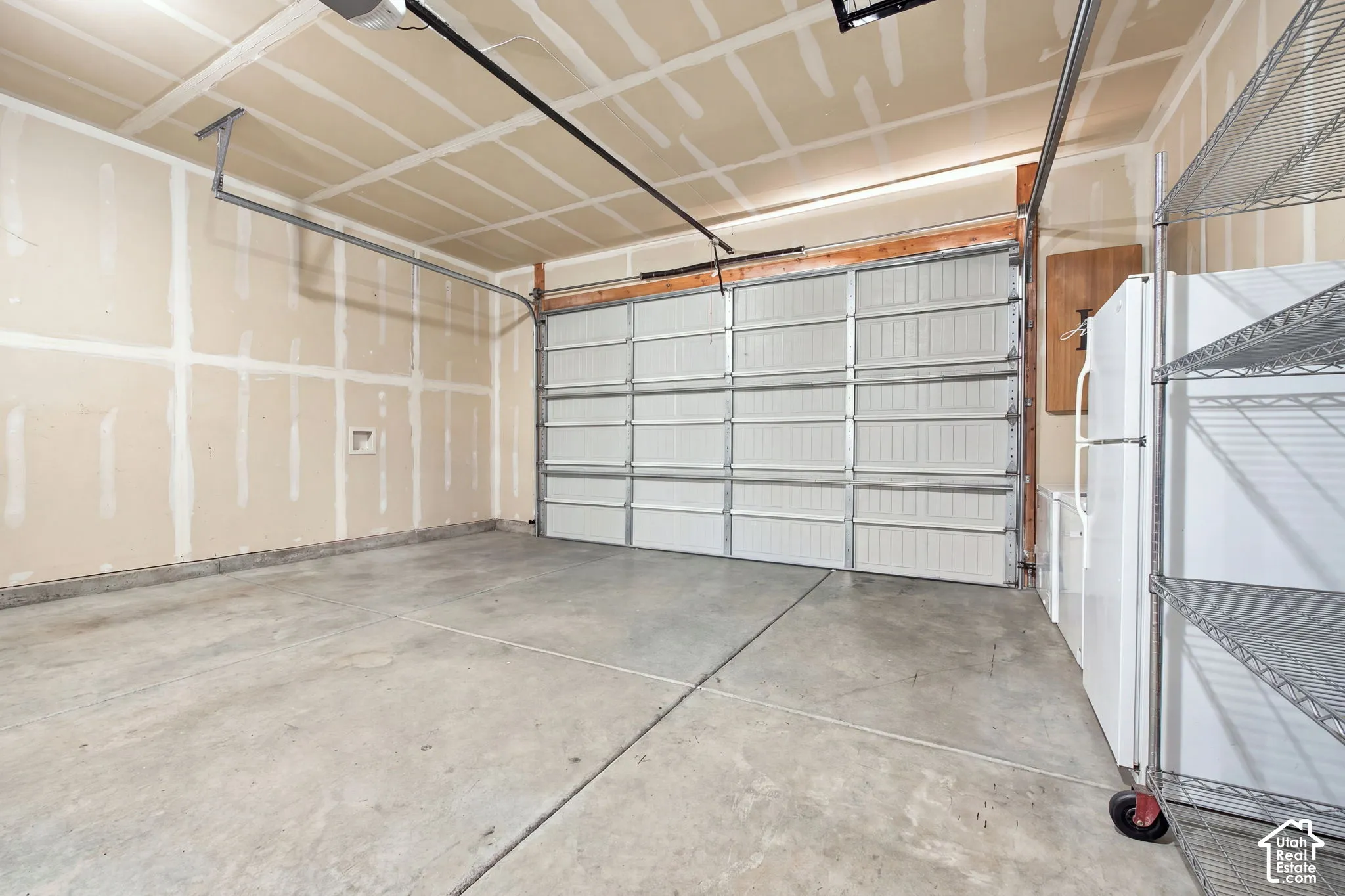 Concrete flooring, unfinished walls, overhead garage door, built-in wire shelving