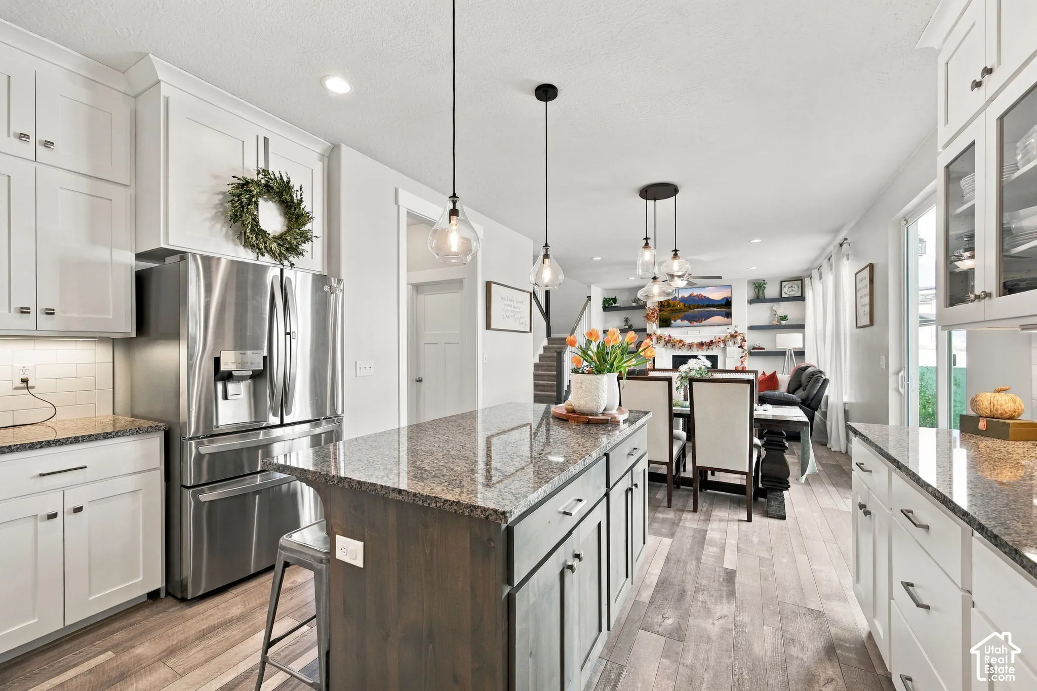 Kitchen featuring white cabinetry, granite countertops, stainless steel refrigerator, and wood-finish flooring