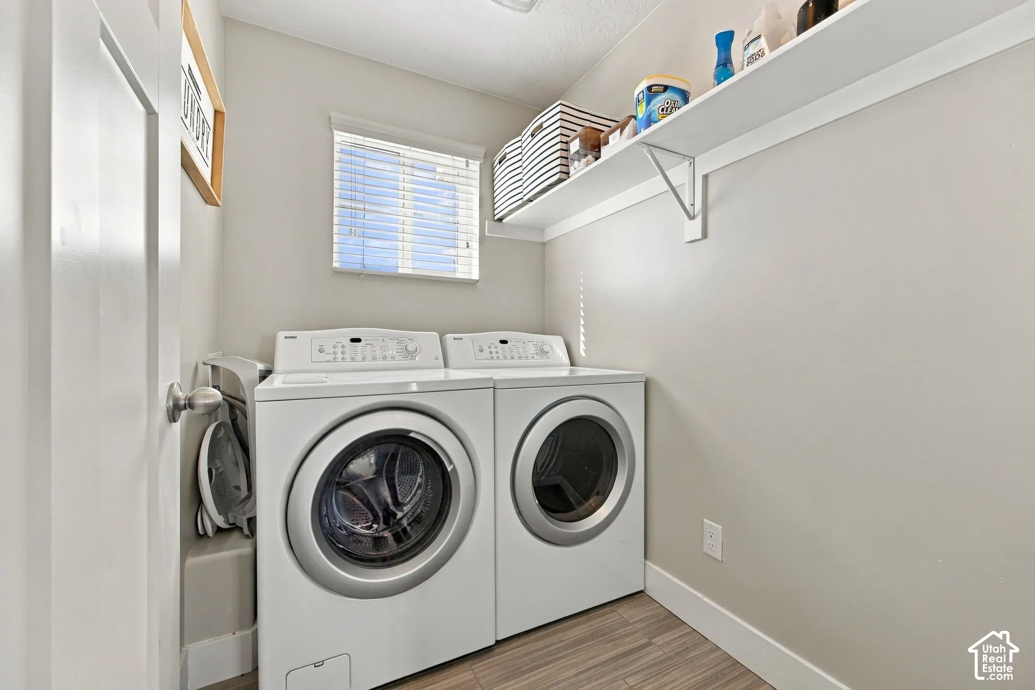 Dedicated laundry space featuring a window, built-in shelving, and wood-finish flooring