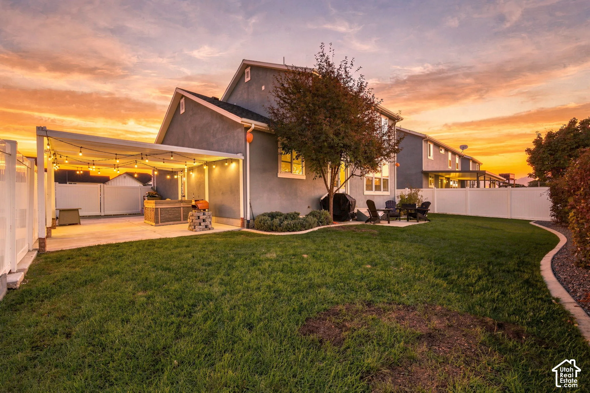 Expansive grass lawn with a paved patio, covered outdoor entertaining area, and perimeter fencing