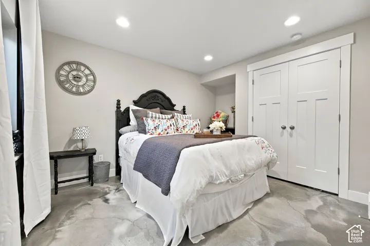 Recessed lighting illuminates the concrete flooring and double-door closet with trim