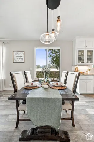 Wood-finish flooring, white cabinetry with glass-front uppers, and clear glass pendant lighting