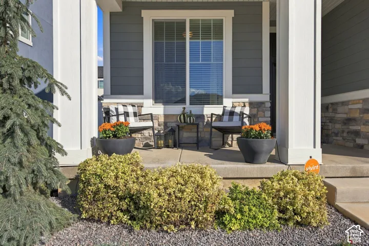 Front porch with white columns, stone accents, and siding