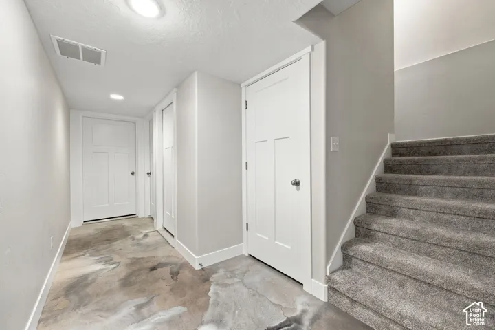 Carpeted staircase, recessed lighting, white interior doors, and stained concrete flooring