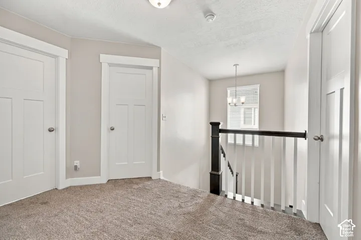 Carpeted landing featuring white paneled doors with contrasting trim, a two-tone stair railing, and a window with blinds