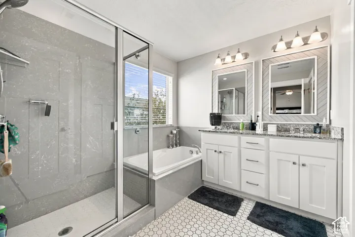 Dual vanity with granite countertops, white cabinetry, and framed mirrors