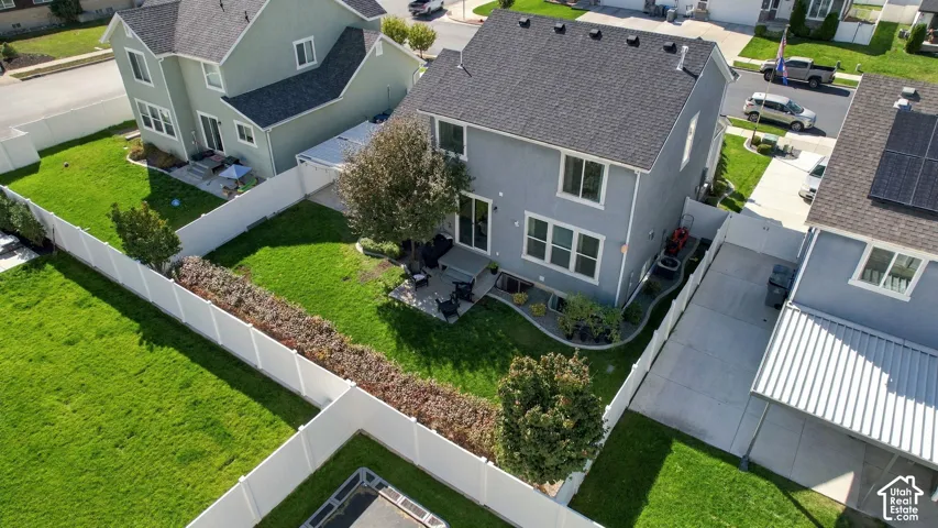 Fenced backyard with a concrete patio, mature trees, and landscaping