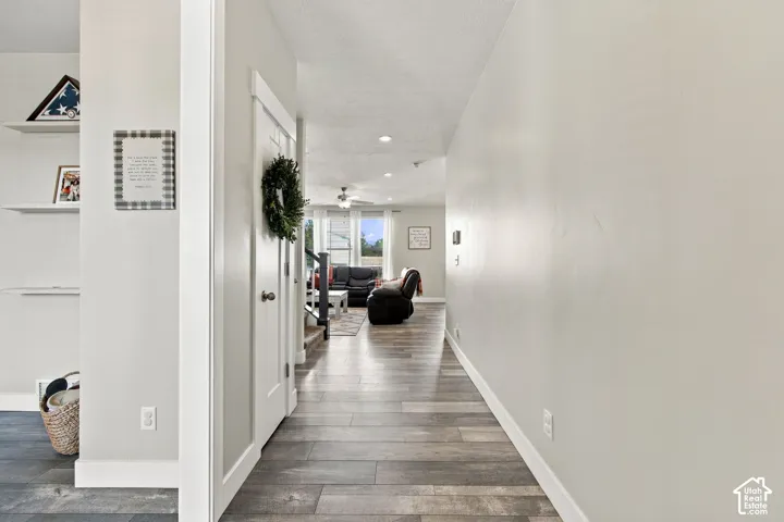 Wood-finish flooring extending throughout, leading to an open living area with recessed lighting