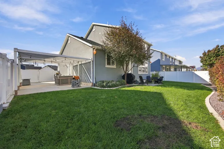 Expansive backyard featuring a lush lawn, concrete patio, and a covered outdoor structure