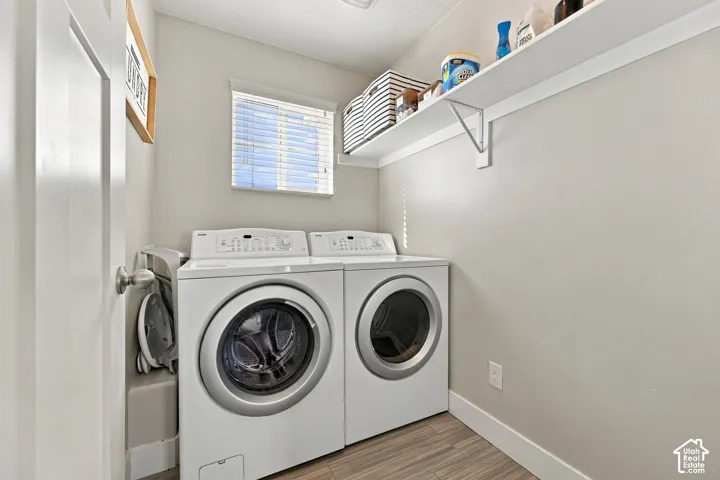 Dedicated laundry space featuring a window, built-in shelving, and wood-finish flooring
