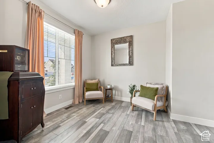 Light-toned wall paint, crown molding, wood-finish flooring, and a large window with blinds