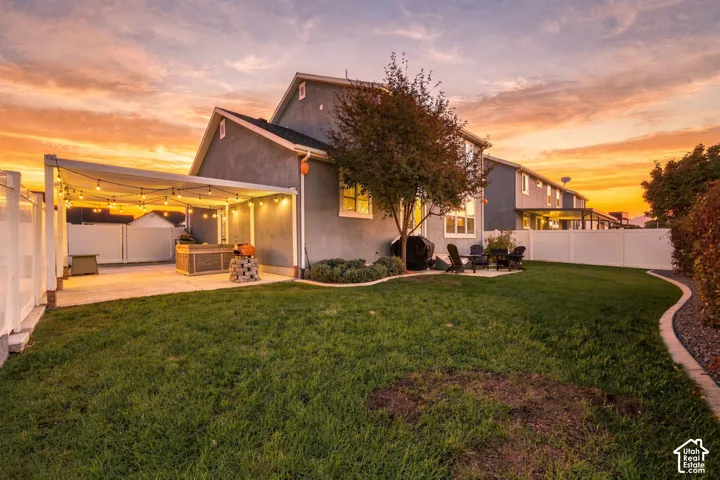 Expansive grass lawn with a paved patio, covered outdoor entertaining area, and perimeter fencing