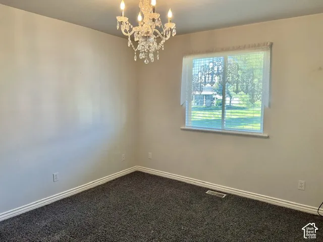 Textured carpet flooring, white trim, and a decorative chandelier