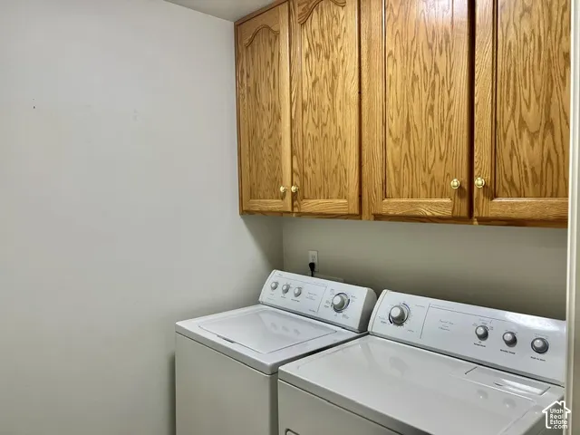 Built-in wood-finish cabinetry provides storage above the laundry appliances