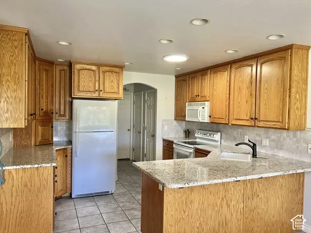 Kitchen featuring wood cabinetry, granite-style countertops, tile flooring, recessed lighting, and a tile backsplash