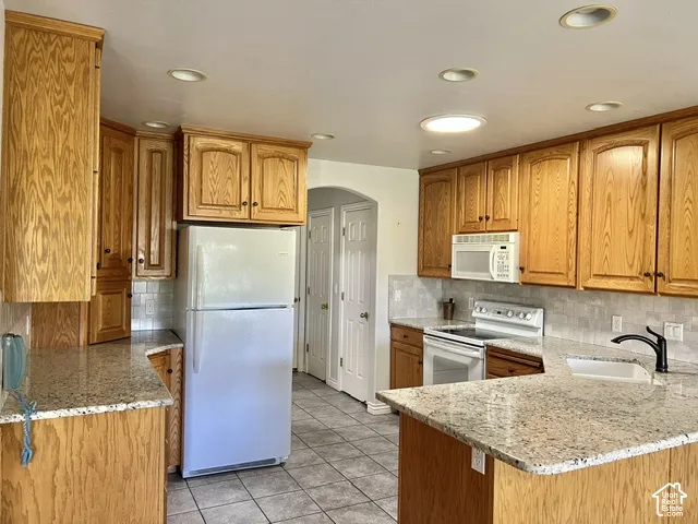 Kitchen featuring wood cabinetry, granite-style countertops, tile flooring, recessed lighting, and a ceramic tile backsplash