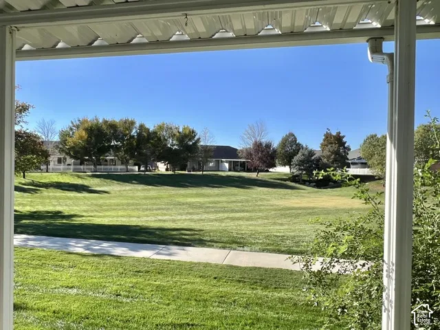 Expansive green space with a paved pathway, mature trees, and a white picket fence