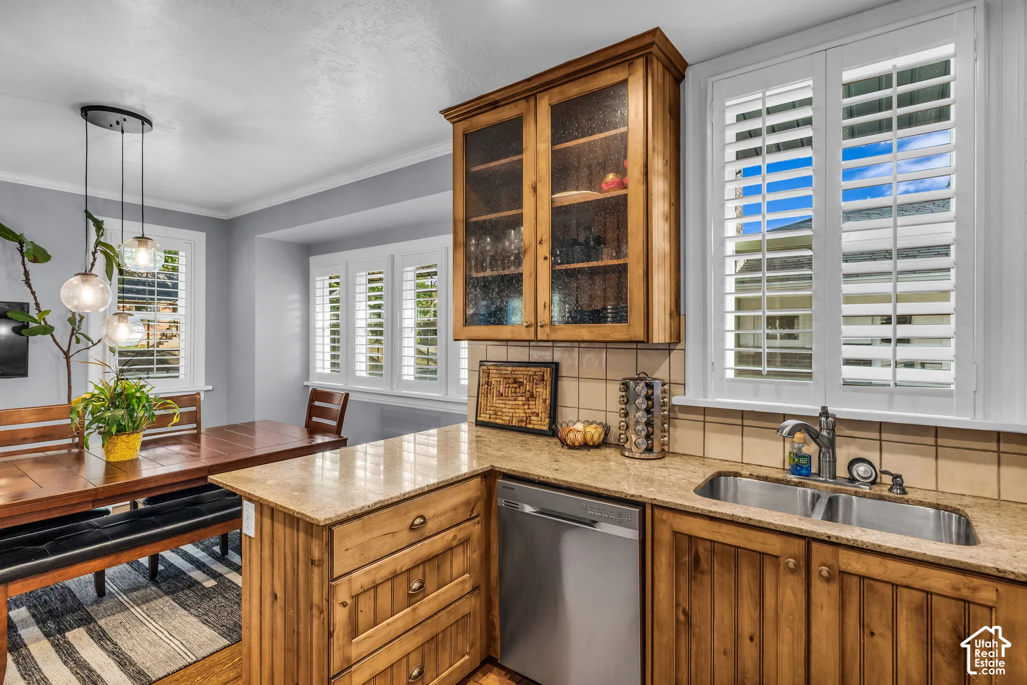 Custom wood cabinetry, stainless steel sink, tile backsplash, and light-toned countertops