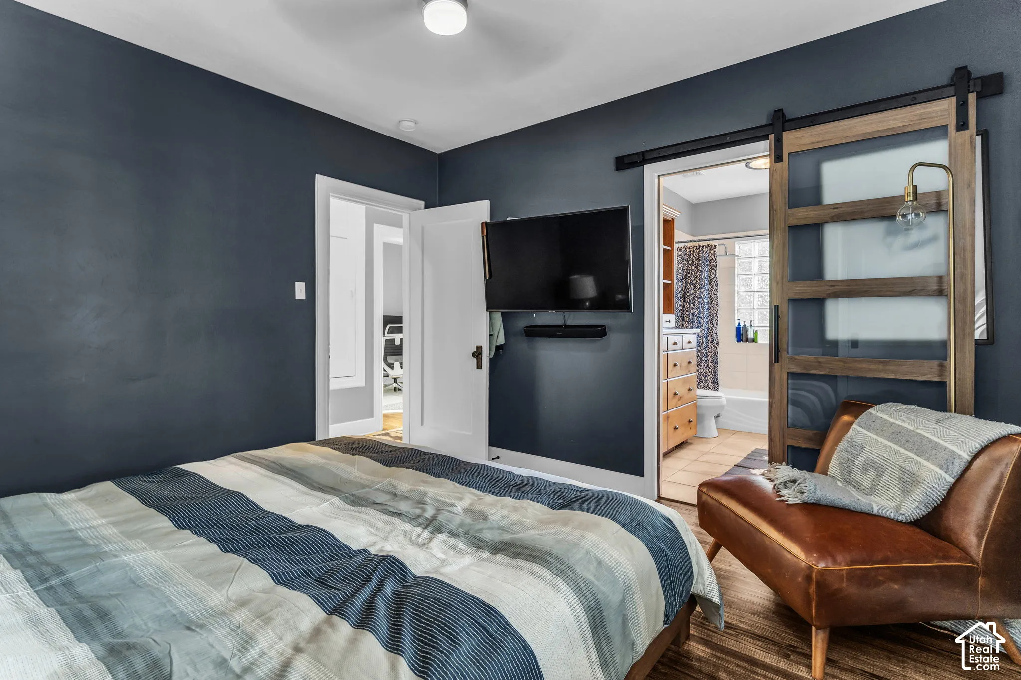 Wood-finish flooring, ceiling light fixture, and a sliding barn door with frosted glass panels