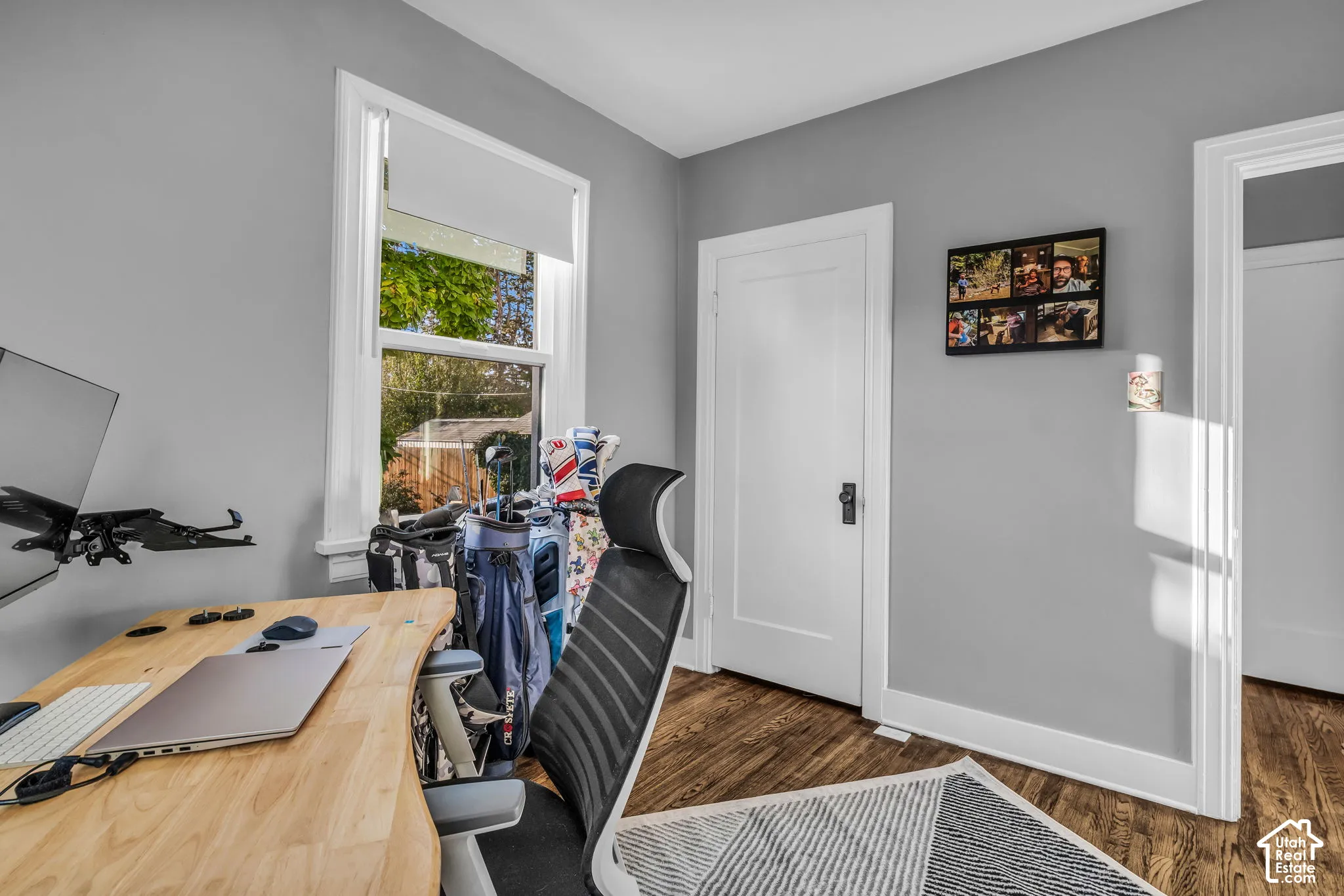 Wood-finish flooring with white trim and a single window with a roller shade