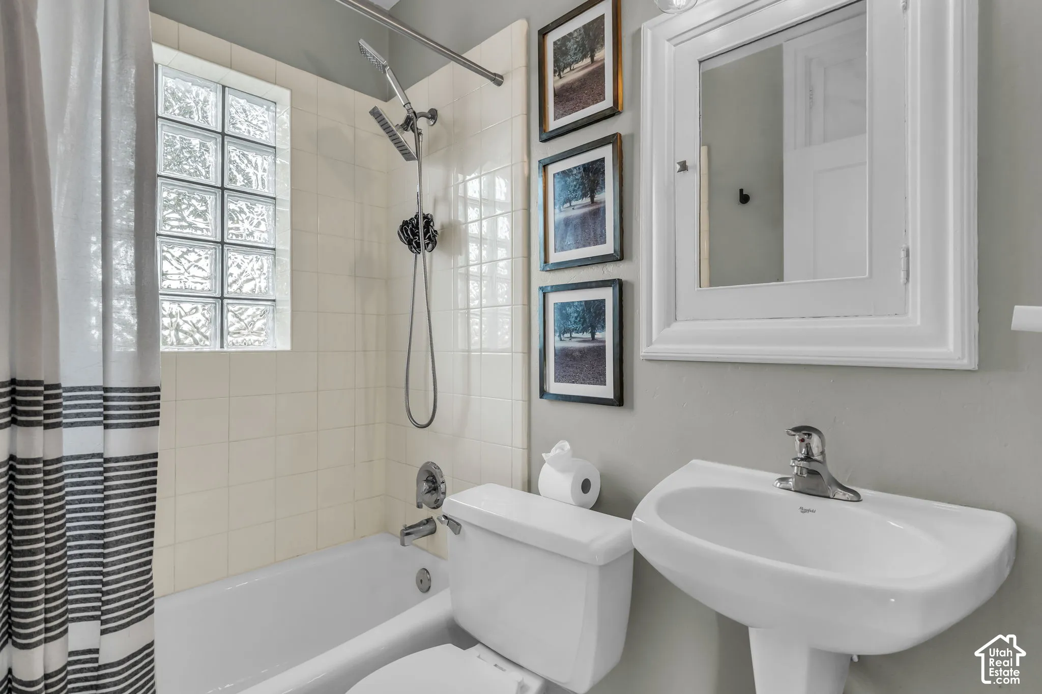 White pedestal sink, chrome faucet, white framed mirror, glass block window, and white subway tile surround
