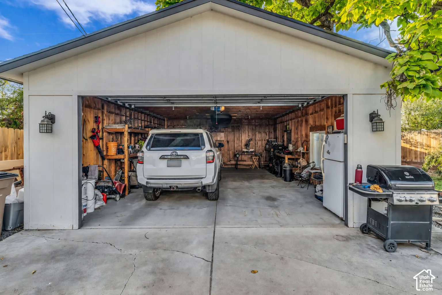 Two-car garage with a concrete driveway, board and batten siding, and exterior wall sconces