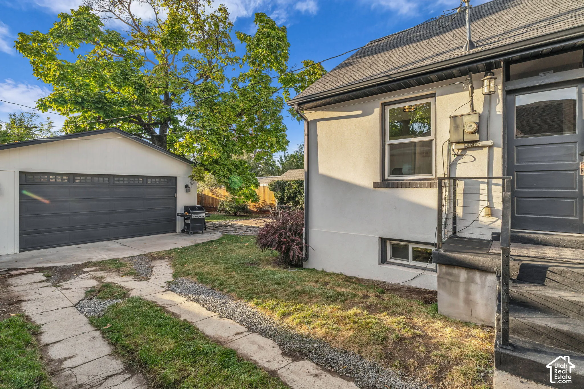 Detached garage, asphalt shingle roof, painted stucco exterior, multi-pane windows, and black exterior door