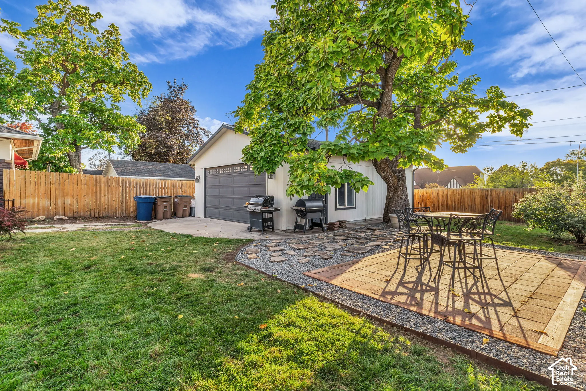Expansive backyard with a manicured lawn, a detached garage featuring a dark gray door, and a dedicated patio area