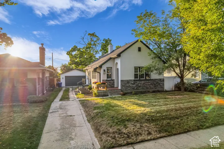 Charming cottage-style home featuring a stone and stucco exterior, pitched roof with gable detail, and multi-pane windows