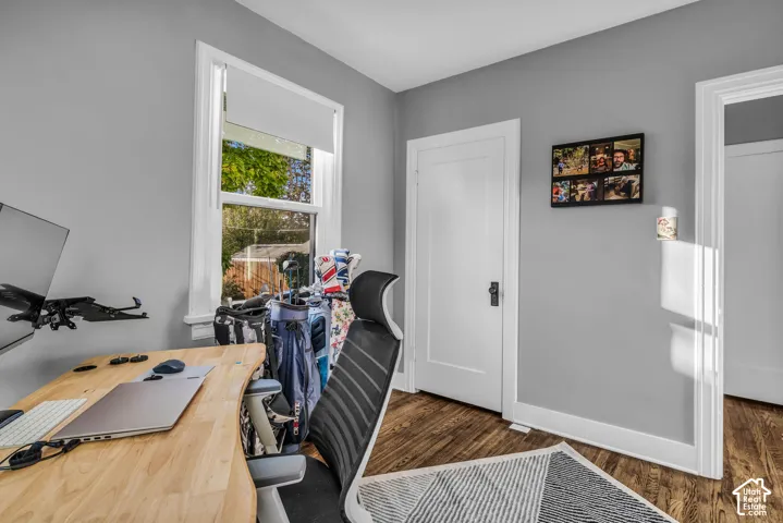 Wood-finish flooring with white trim and a single window with a roller shade