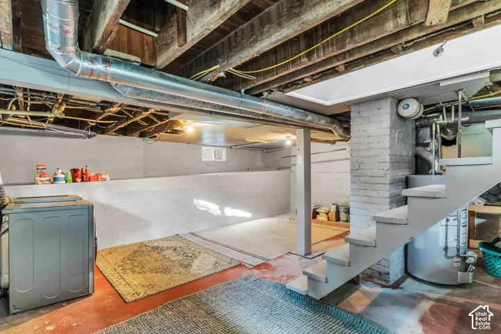 Exposed ceiling joists and ductwork, painted concrete walls, painted brick column, and a fixed staircase
