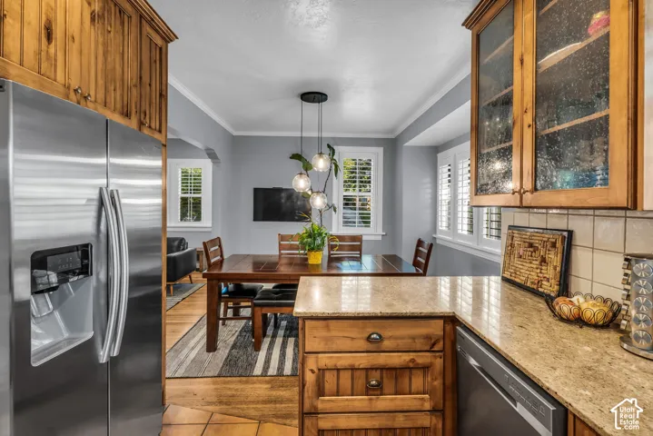 Stainless steel refrigerator, custom wood cabinetry, granite countertops, tile backsplash, and a built-in dishwasher