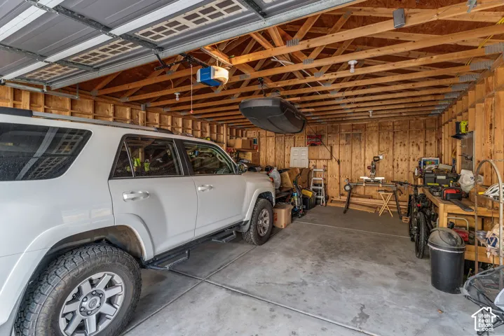 Garage with exposed wood framing, concrete flooring, and an automatic garage door opener