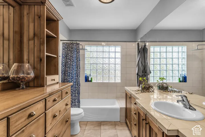 Built-in wood-finish cabinetry with multiple drawers, tiled countertop with integrated sink, and glass block windows