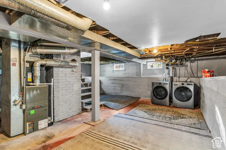 Utility area featuring a furnace, exposed ductwork, and a washing machine with a dryer