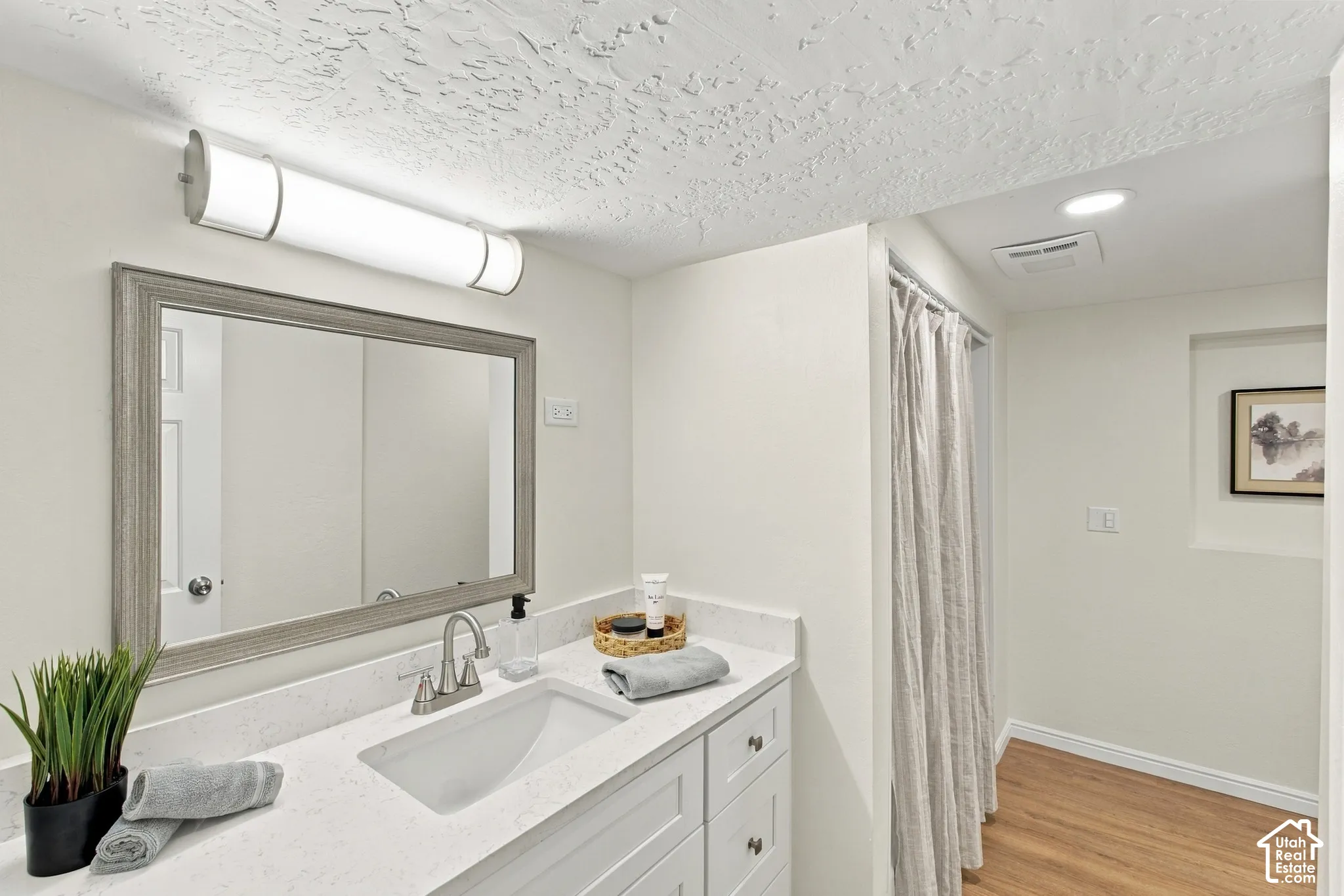 White vanity with shaker-style cabinetry, a rectangular undermount sink, and a quartz countertop
