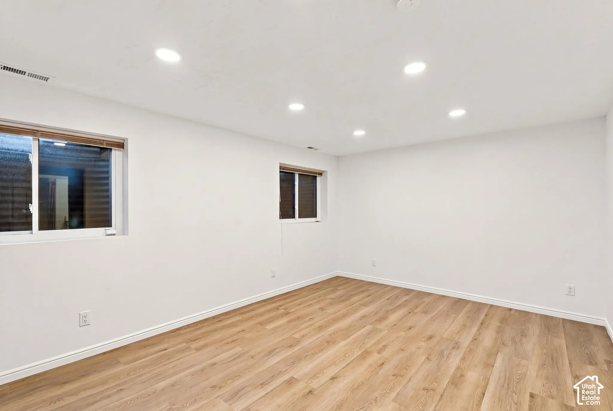Recessed ceiling lighting, wood-finish flooring, and white painted walls
