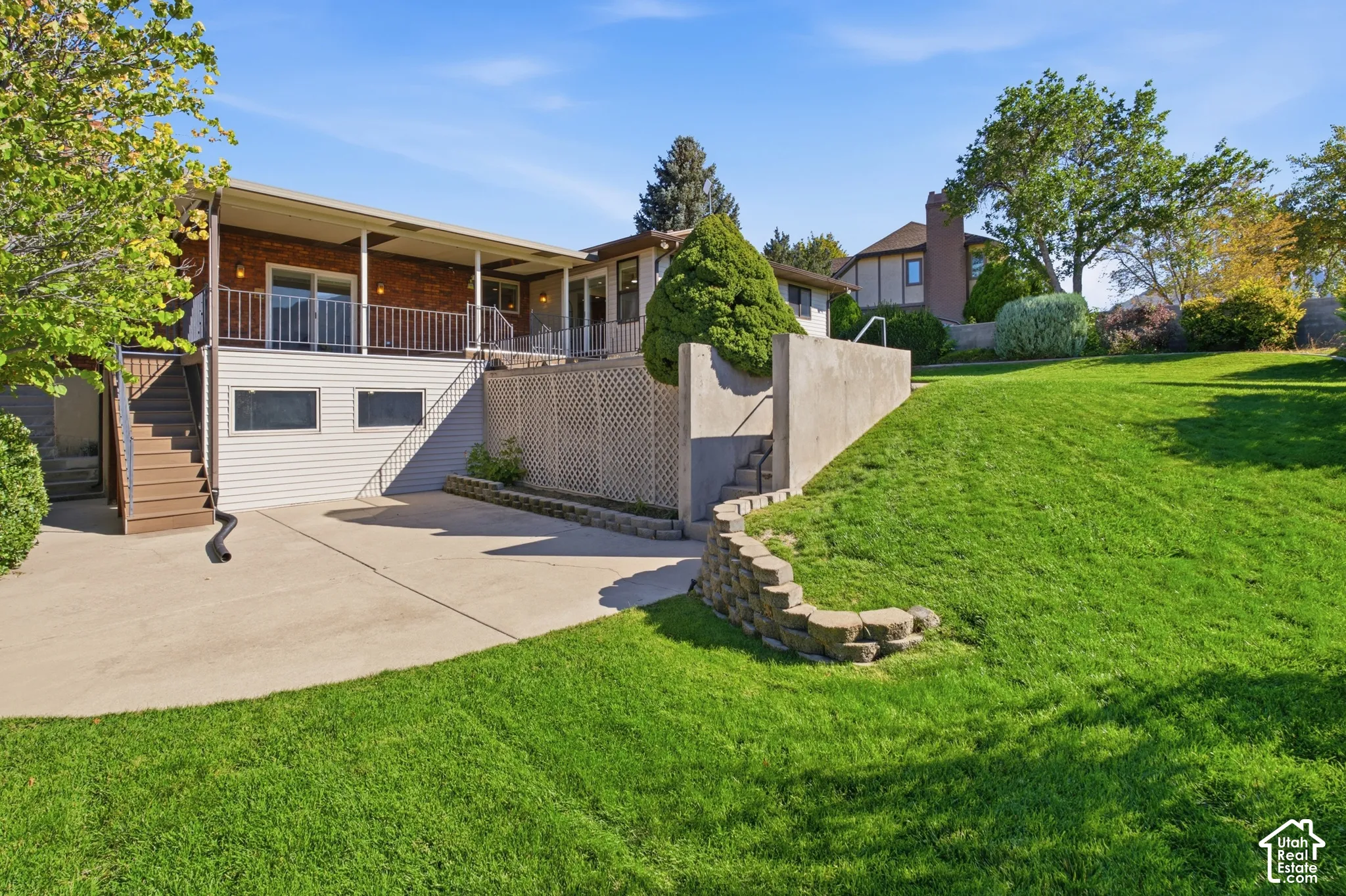 Brick exterior with a covered upper-level patio, featuring a metal railing system and an exterior staircase