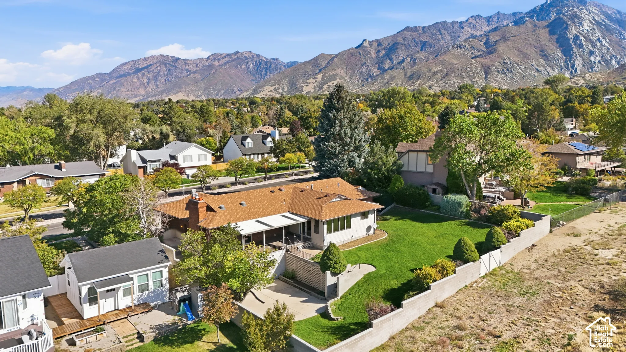 Expansive property featuring a sizable green lawn, mature landscaping, and a mountain backdrop